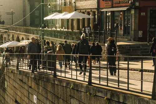 Free People walking along a busy street in Porto, Portugal, basking in warm sunlight. Stock Photo