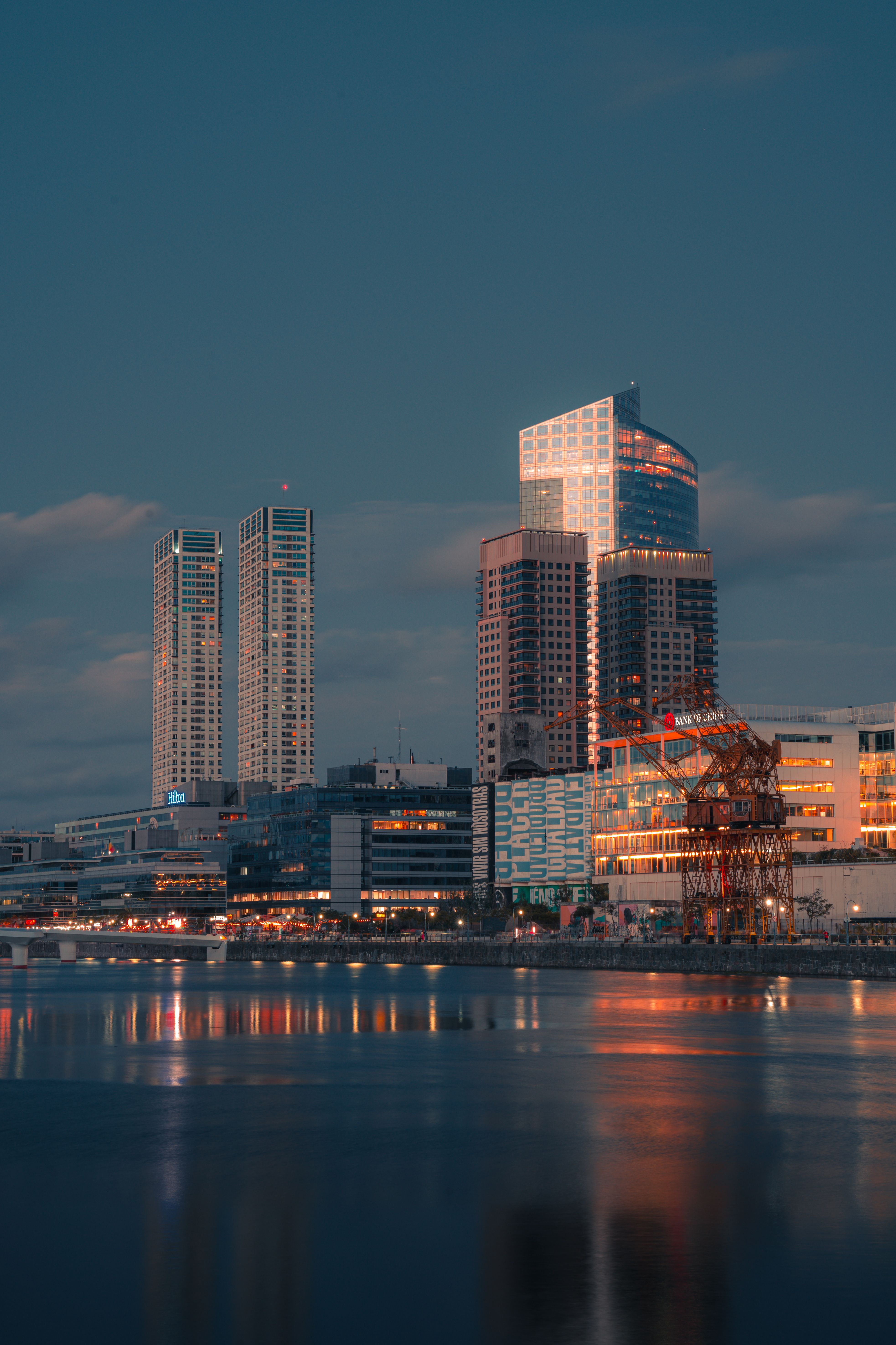 A breathtaking view of skyscrapers reflecting in the river during sunset in a vibrant city.