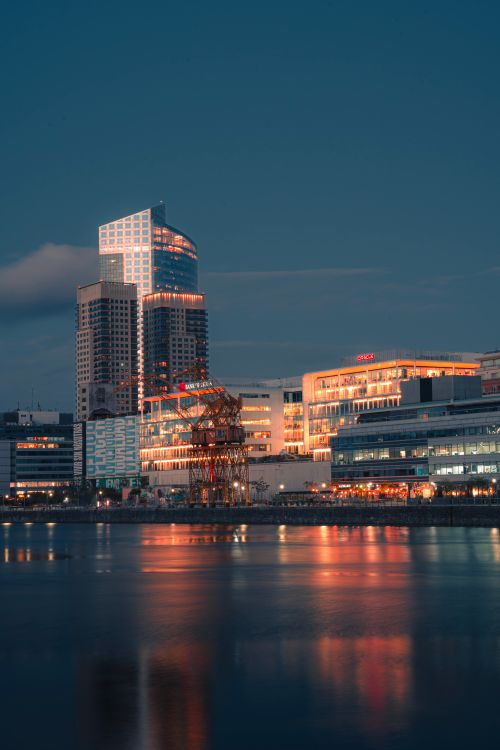 Free A vibrant city skyline at dusk reflecting on a calm river, showcasing modern skyscrapers and urban architecture. Stock Photo