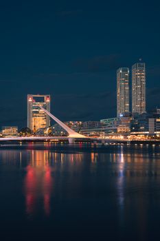 Stunning night view of a cityscape with modern bridge and reflections in the water.