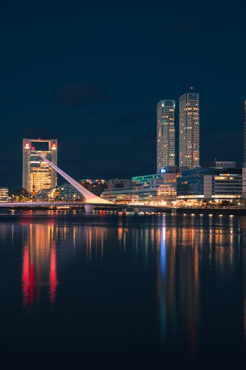 A city skyline at night with a bridge and water