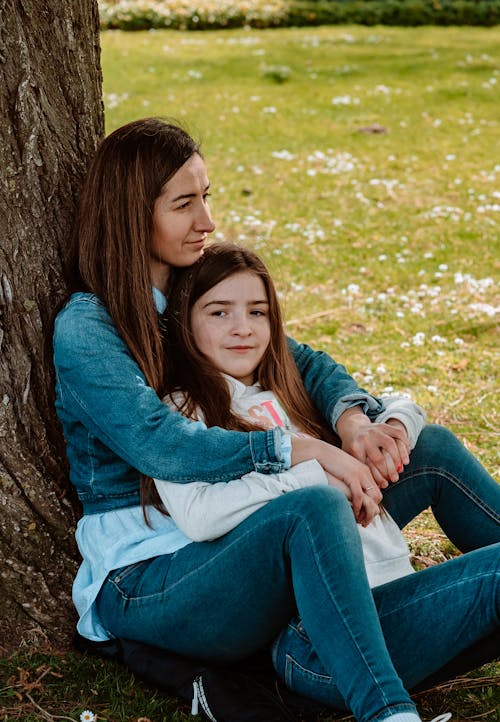 Free A woman and her daughter sitting on the grass Stock Photo