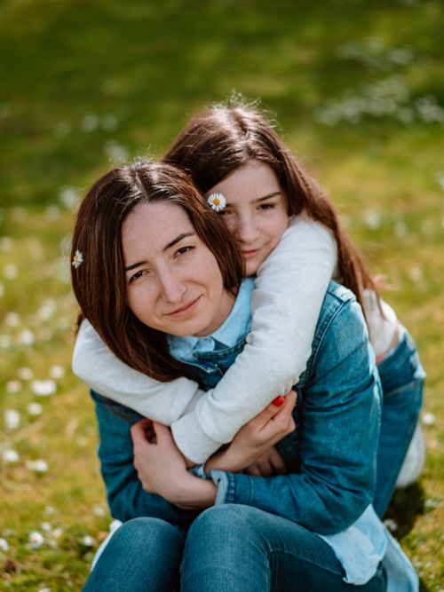 Free Mother and daughter share a loving hug in a sunlit meadow, symbolizing family bonds. Stock Photo