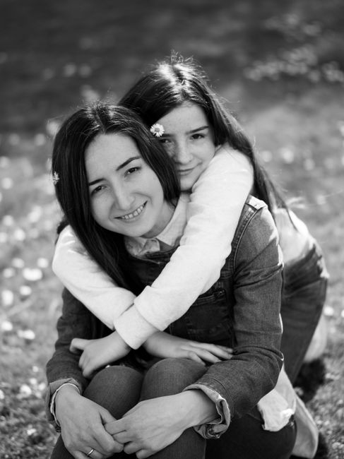A touching black and white portrait of a mother and daughter embracing outdoors.