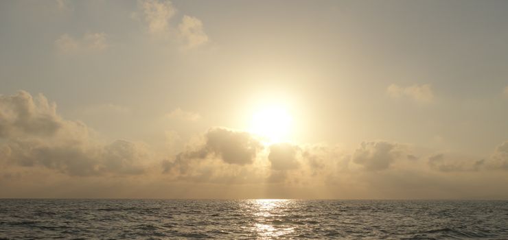 海面上迷人的日出，将金色的色调映照在平静的水域和云层上
