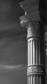 Elegant classical architectural column against a dramatic sky, captured in black and white.