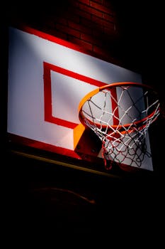 A close-up shot of a basketball hoop against a dark brick wall, highlighting the sport's vibrant energy.