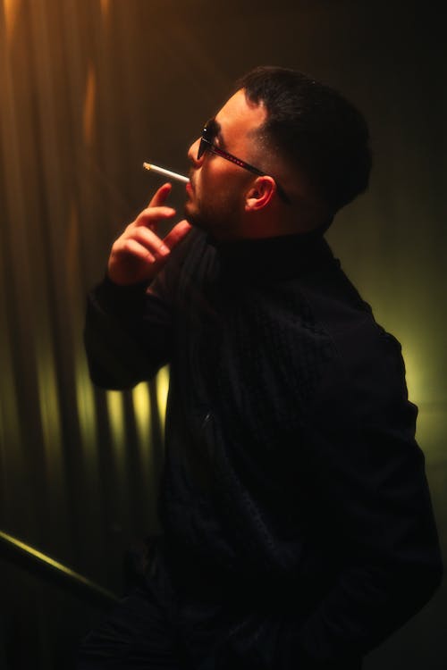 A man smoking a cigarette in a dark room