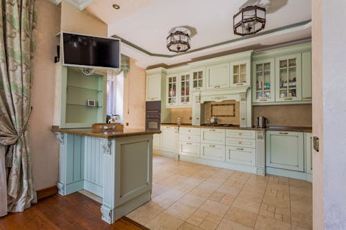 A kitchen with green cabinets and a tv