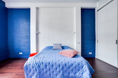 A bedroom with blue walls and white bed