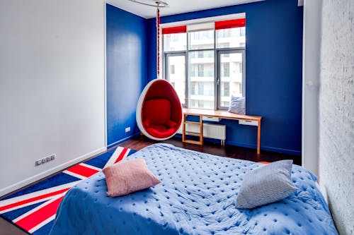 Free A bedroom with a blue and white bed and a flag hanging from the ceiling Stock Photo