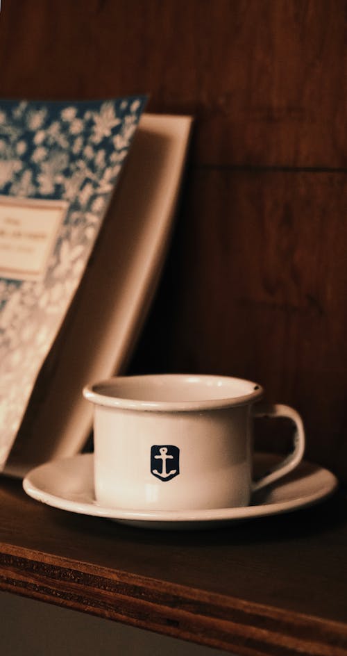 A cup and saucer on a shelf next to a book
