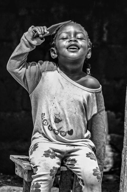 Free A black and white photo of a child sitting on a stool Stock Photo