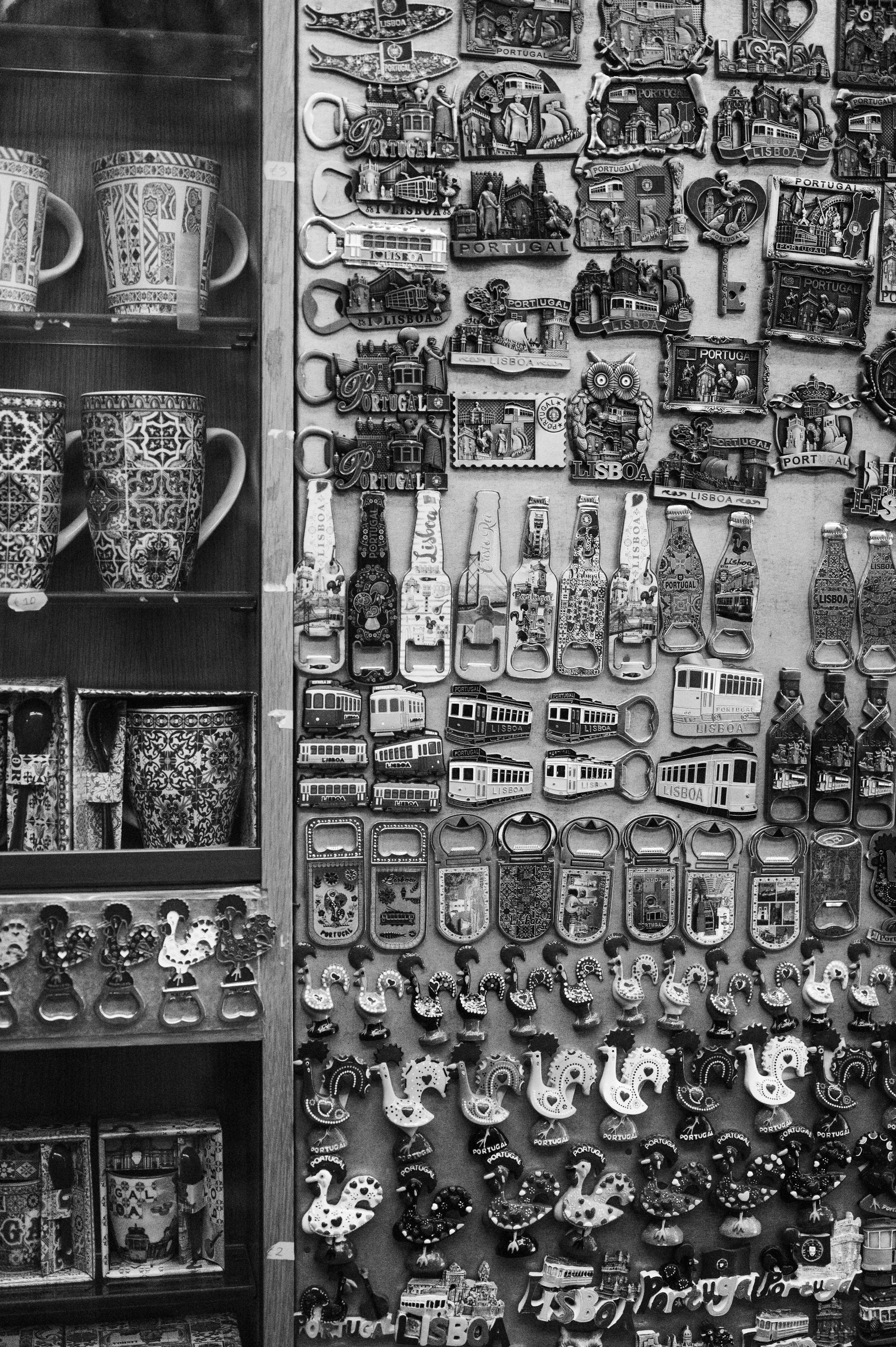 Black and white display of travel souvenir magnets and mugs on a market stand.
