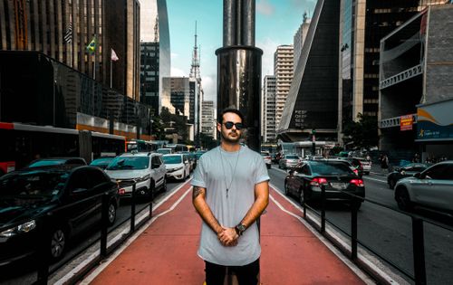 Free A man stands confidently on a bustling city street with skyscrapers all around. Stock Photo