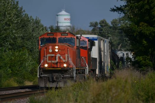 Canadian freight train passing through Boone, Iowa, surrounded by lush greenery.