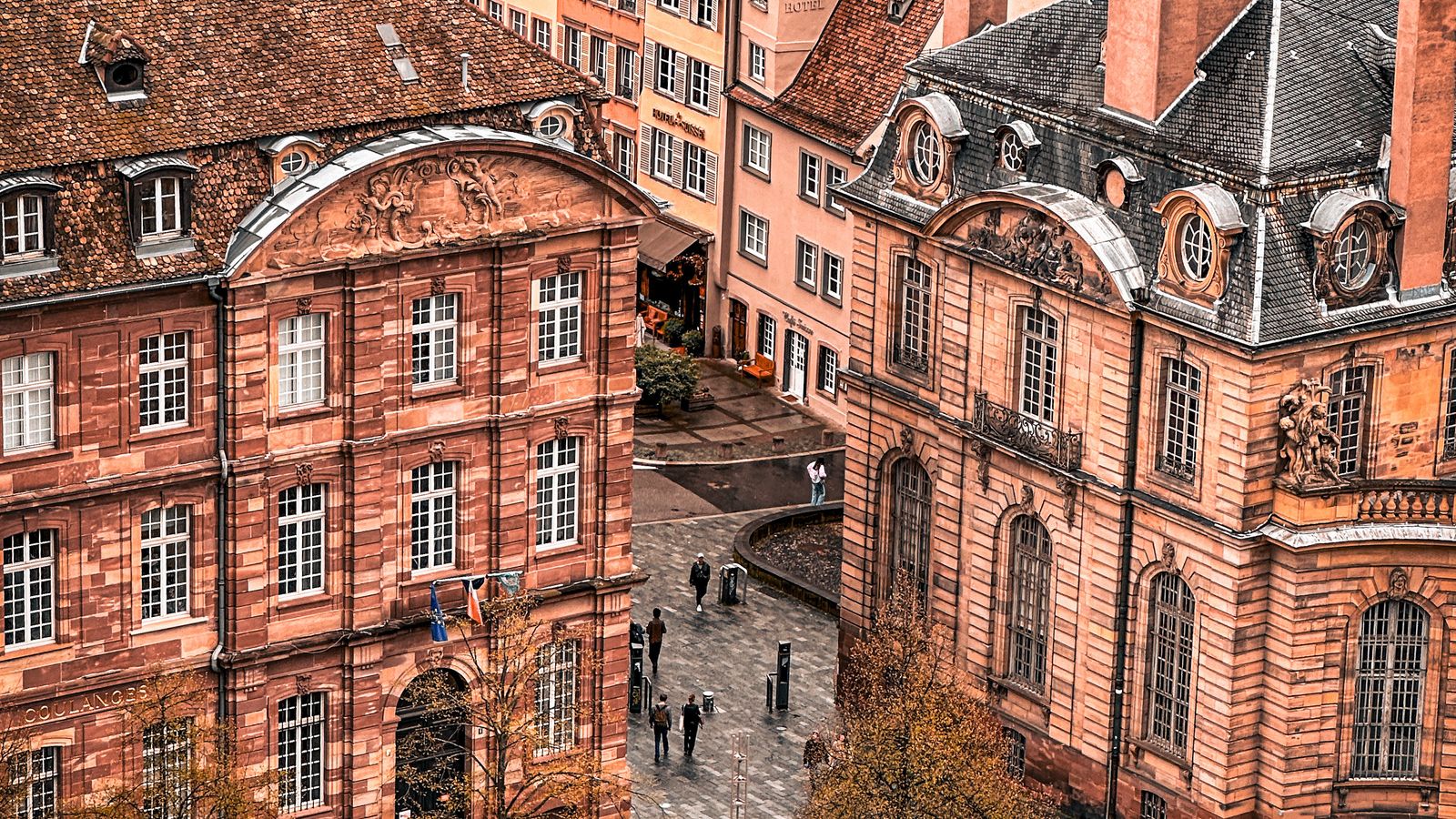 Vue aérienne de toitures et d'une place pavée de Strasbourg, bâti dense et régulier.