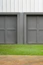 特写镜头中，两扇现代灰色车库门映衬着草地和人行道