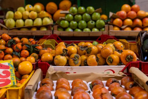 Free Vibrant fresh fruits like persimmons and tangerines at a market in Rome, Italy. Stock Photo
