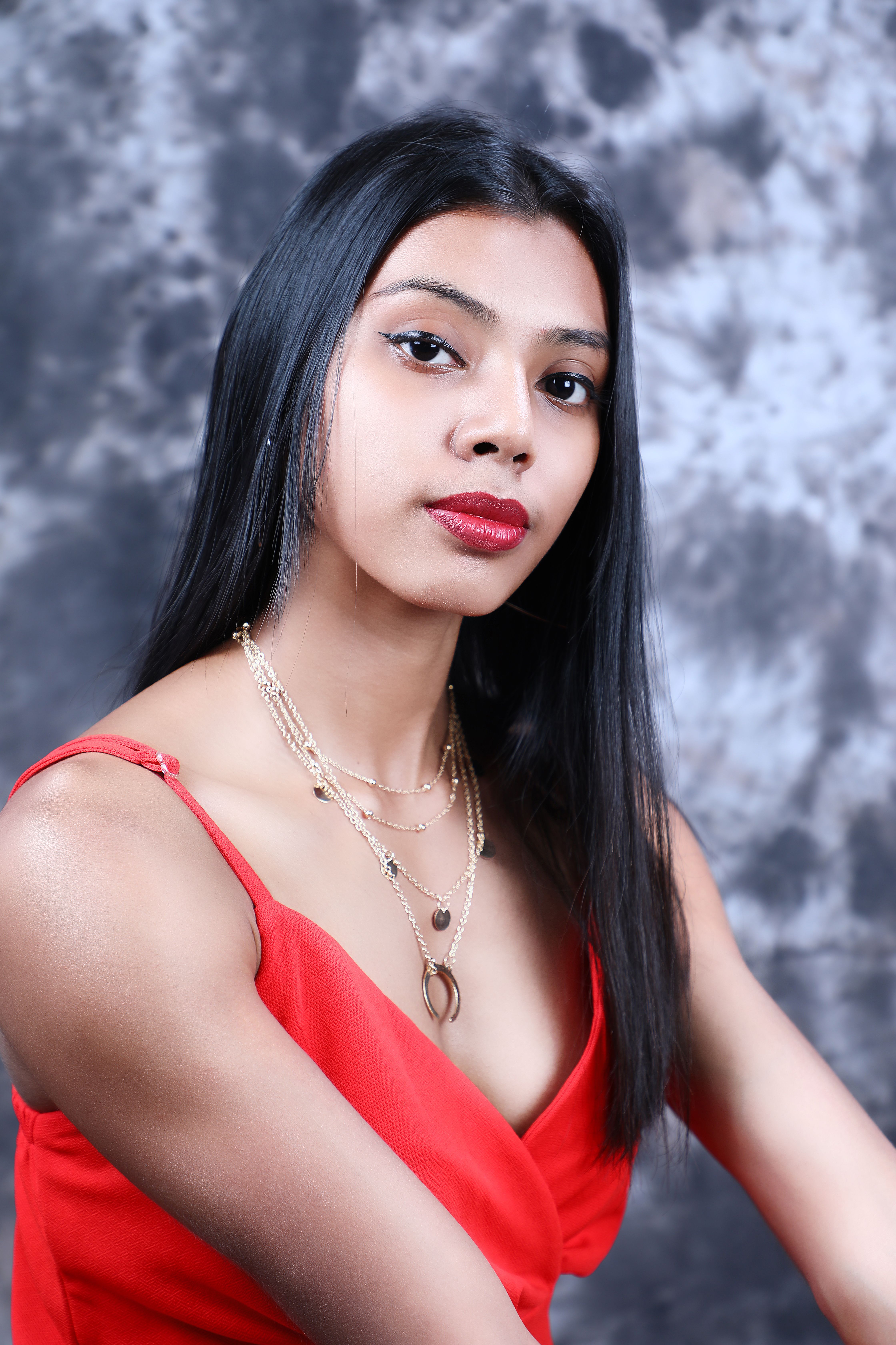 Portrait of a beautiful woman with long hair and red dress against a textured background.