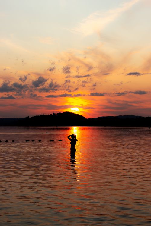 Woman Standing Knee Deep in Water at Sunset · Free Stock Photo