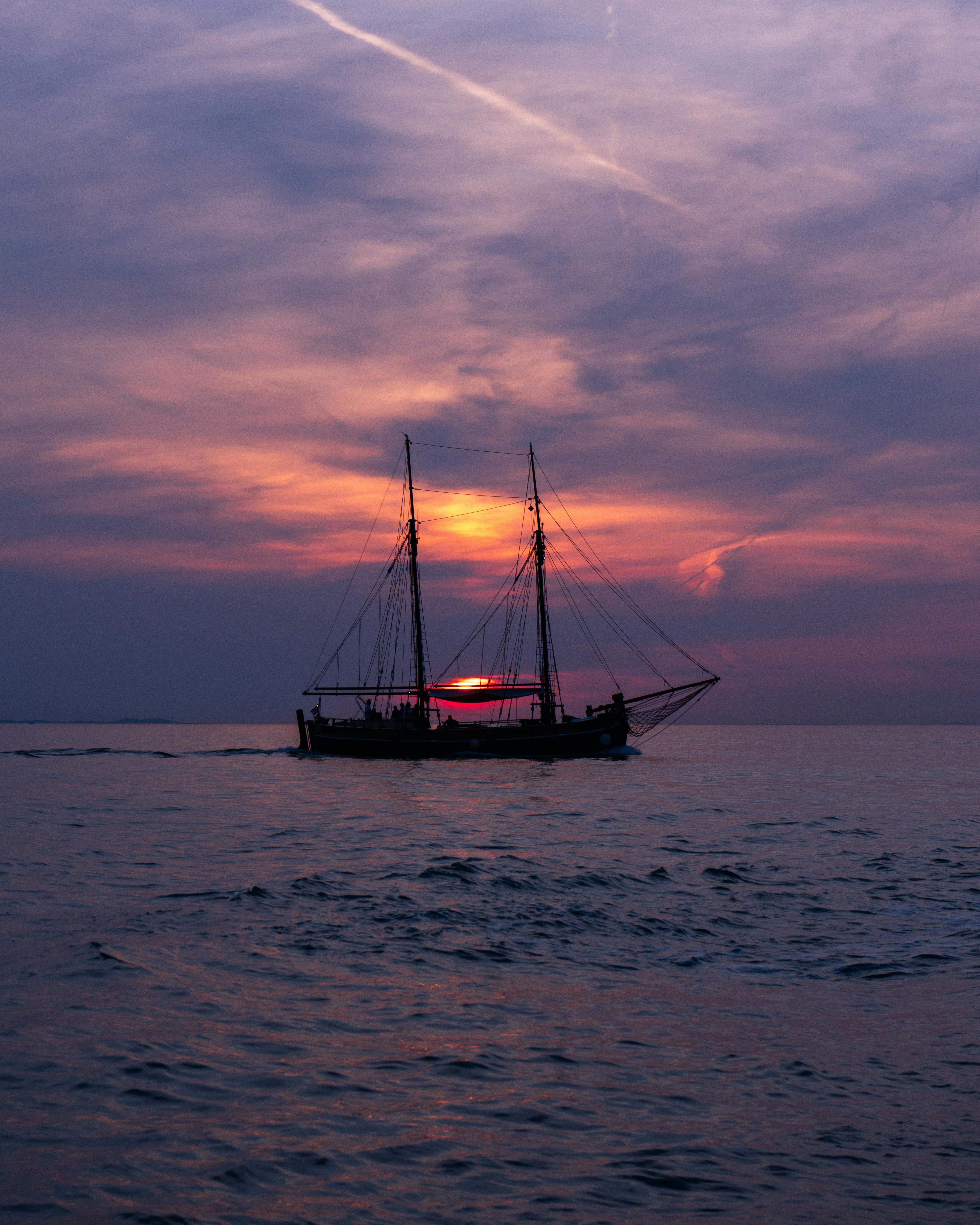 A dramatic silhouette of a sailing ship against the colorful sunset in Zadar, Croatia.
