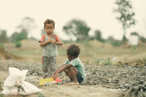 Two children playing on the ground near a river