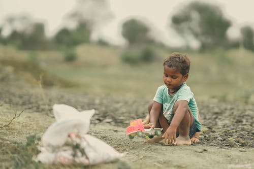 A little boy sitting on the ground with a bag