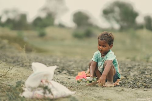 Free A young boy engaged in imaginative play with a toy car in a serene rural setting. Stock Photo