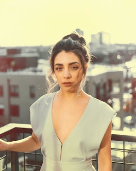 一位时尚女性在阳光明媚的阳台上摆姿势，背景是城市景观