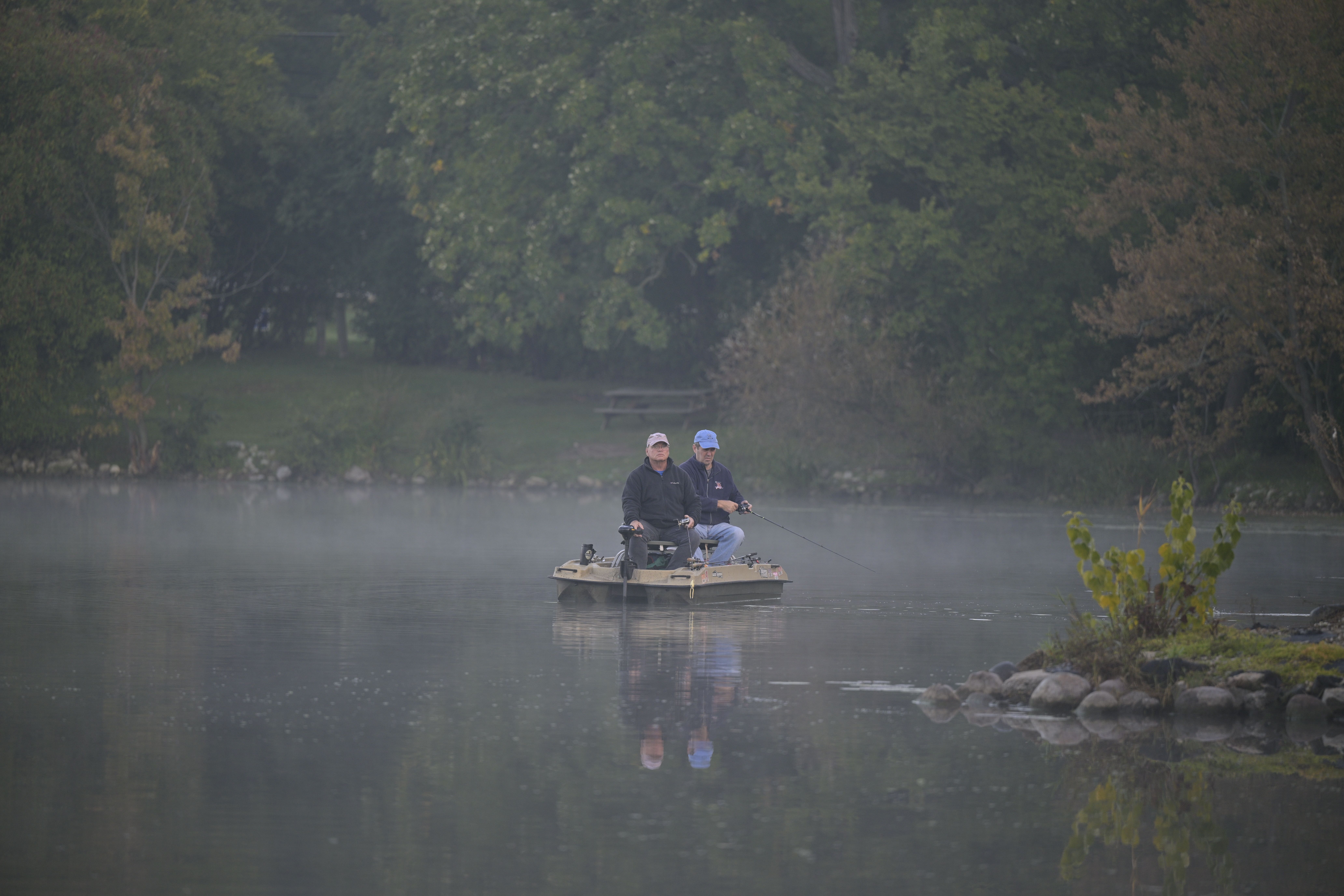 Two anglers fishing together on a misty lake