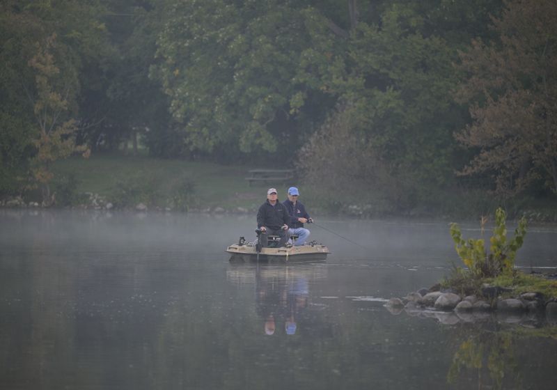 Two anglers fishing together on a misty lake