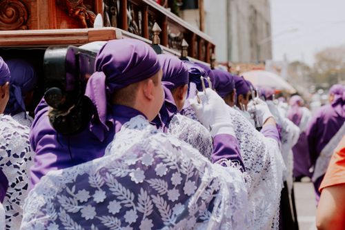 Free Participants in purple attire carry a platform during a Holy Week procession outdoors. Stock Photo