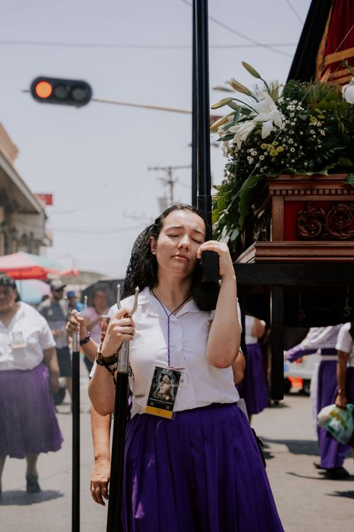 Free A woman in traditional attire participating in a street procession, carrying a floral decorated float. Stock Photo