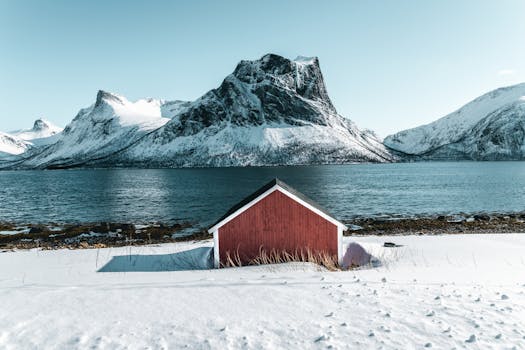 白雪皑皑的山脉、湖泊与红色的谷仓共同构成了一幅宁静的冬日景象
