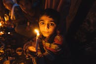 在巴基斯坦拉合尔，一个孩子在温暖昏暗的气氛中手持蜡烛