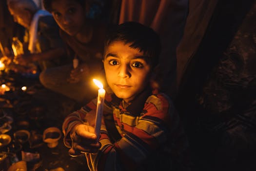 在巴基斯坦拉合尔，一个孩子在温暖昏暗的气氛中手持蜡烛