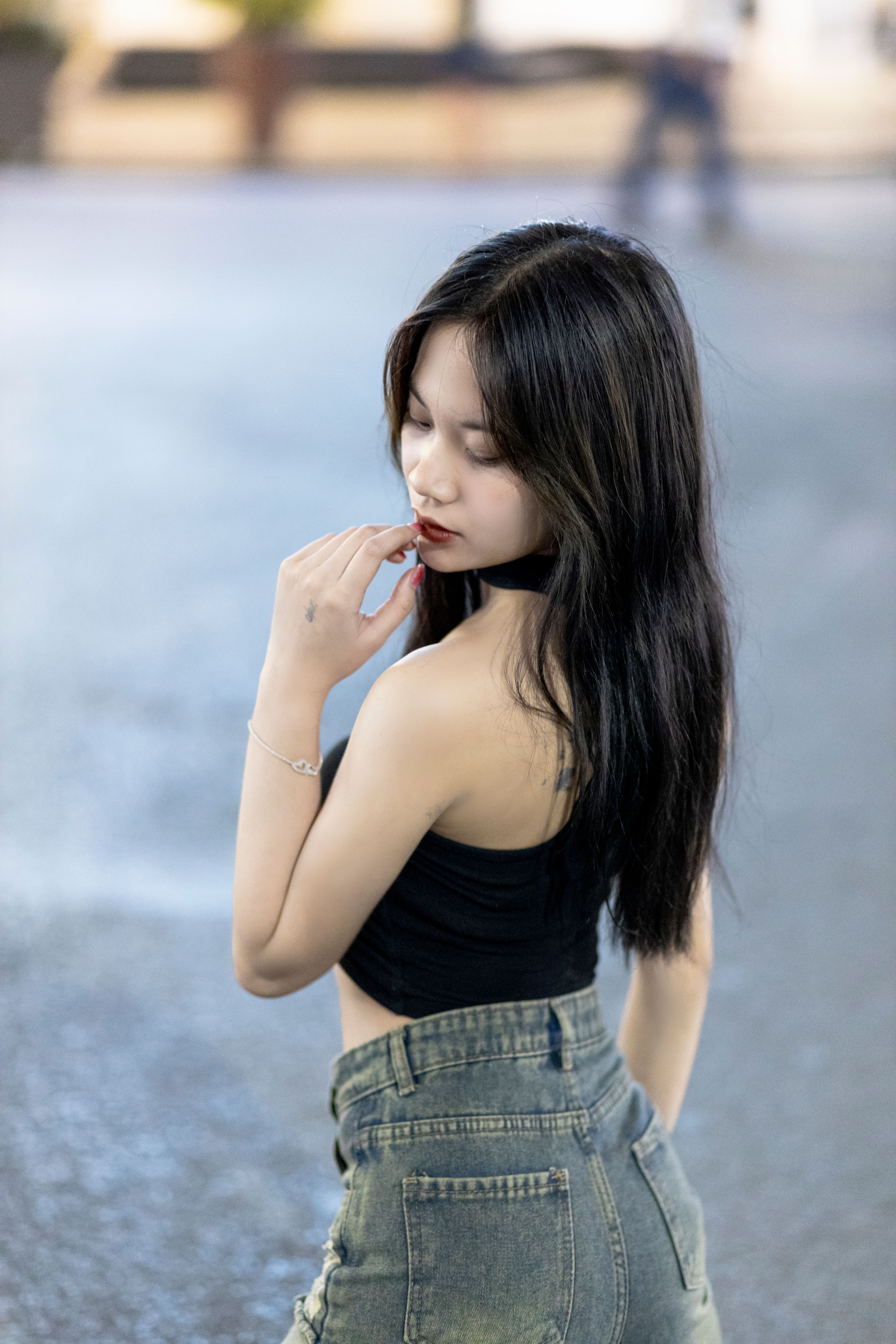 Young Asian woman posing confidently in an urban environment, exuding fashion and elegance.