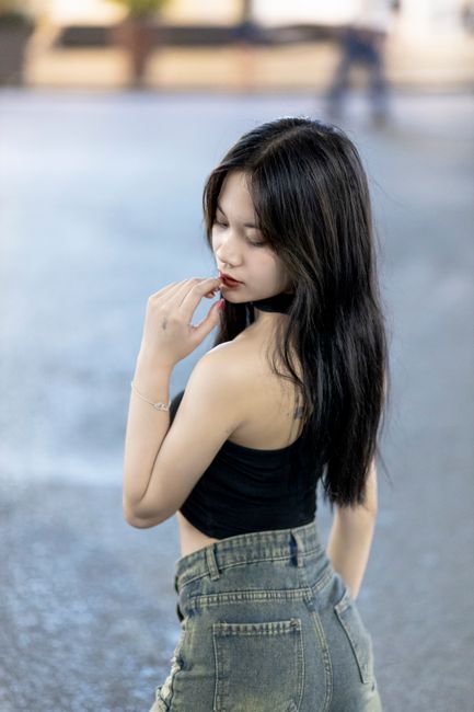 Young Asian woman posing confidently in an urban environment, exuding fashion and elegance.
