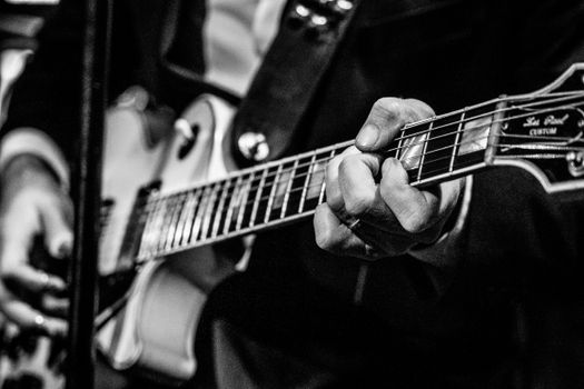 A musician passionately plays an electric guitar in a black and white setting.