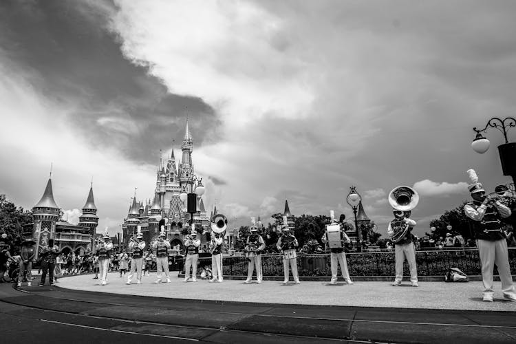 People Playing On The Instruments By A Castle In Black And White