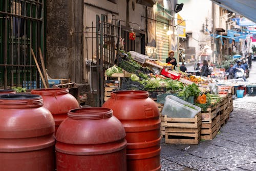 A street with many red barrels and vegetables