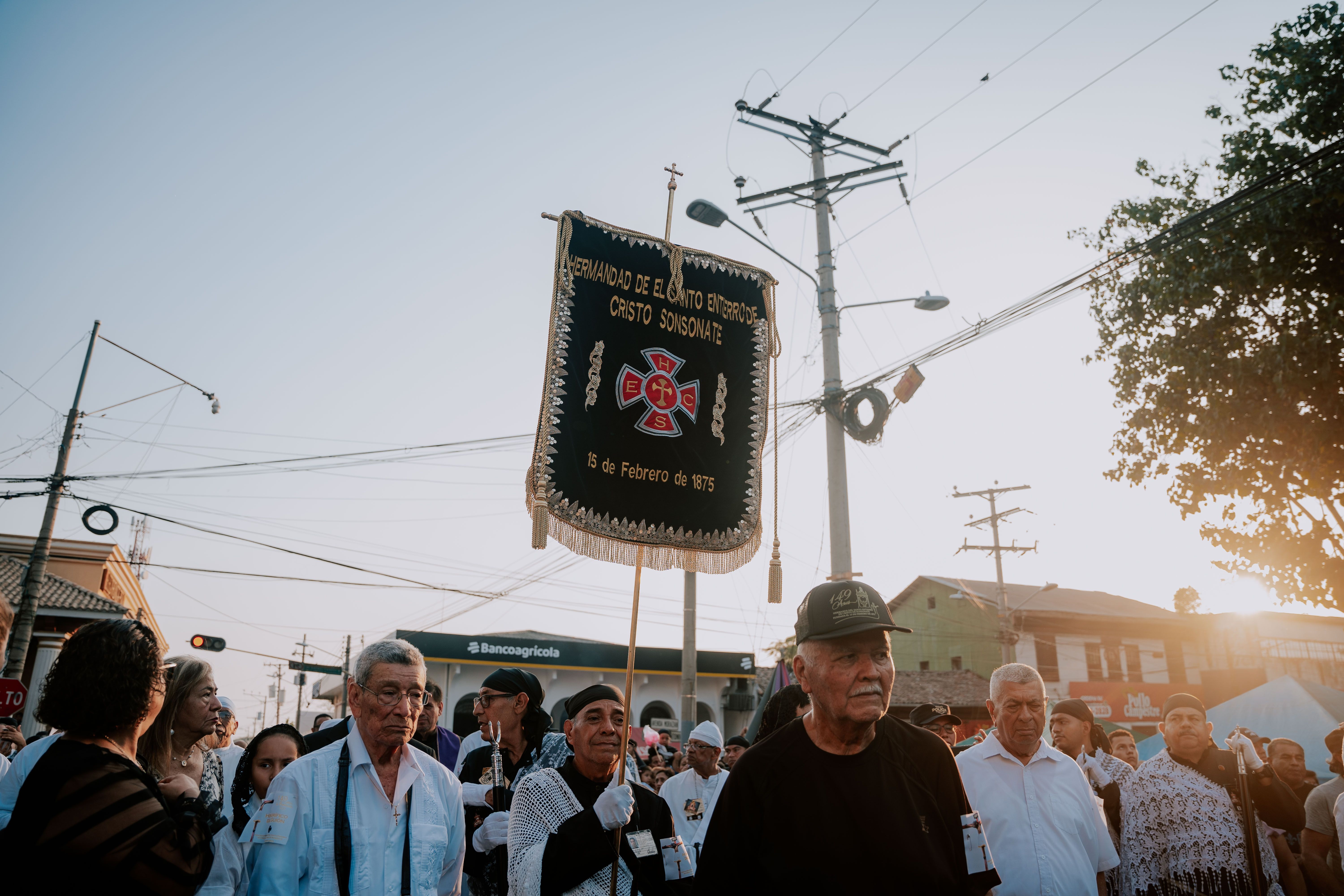 Crowd of People Walking Through a Street of a City Holding up a Sign ...