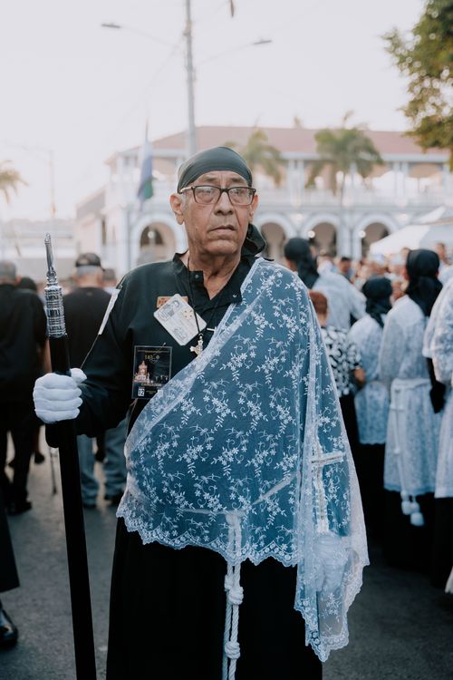 Free An elderly man in traditional clothing participates in a religious parade, holding a staff. Stock Photo