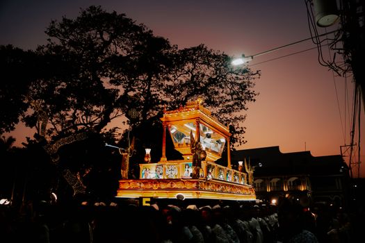 A vibrant religious procession with illuminated shrine during dusk, capturing spirituality and celebration.