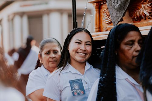 Free Women in white uniforms participate in a traditional outdoor ceremony, smiling and engaged. Stock Photo