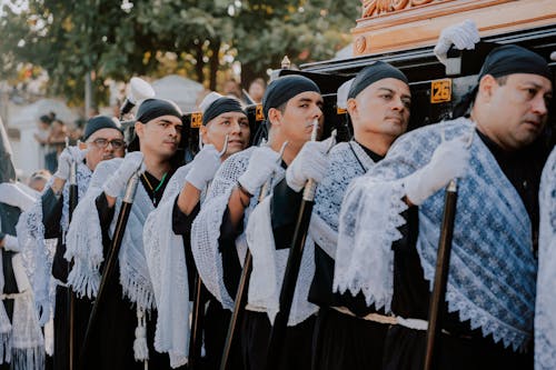 A group of men dressed in black and white are standing in front of a coffin