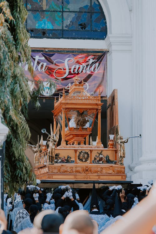 A wooden statue of the baby Jesus is displayed in front of a church