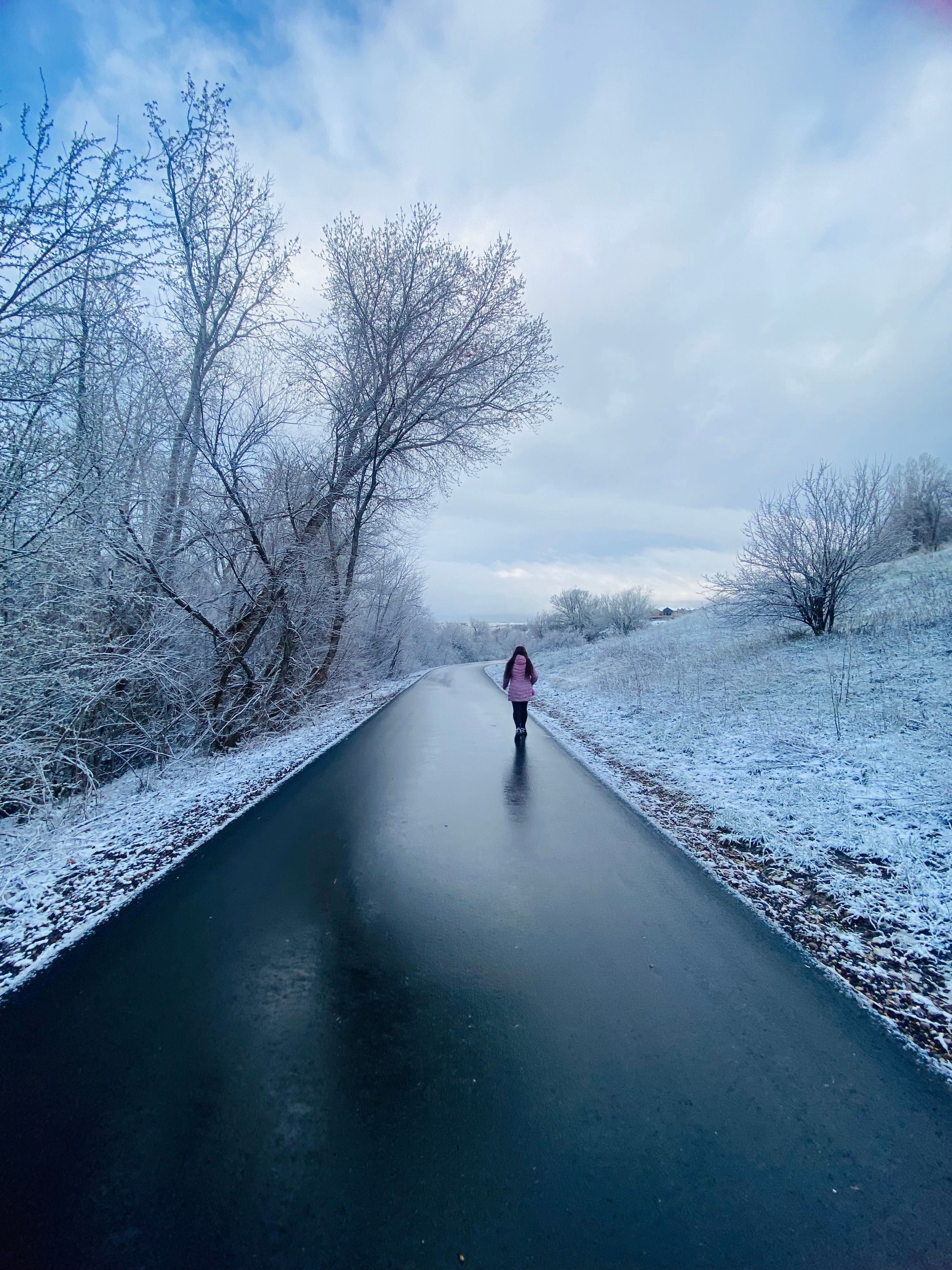 A lone woman walks down a snowy rural road in South Ogden, Utah, creating a serene winter scene.