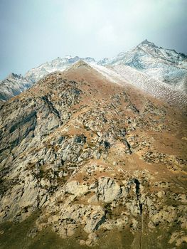 Stunning aerial view of a rugged, barren mountain range with eroded rocks and snowy peaks.